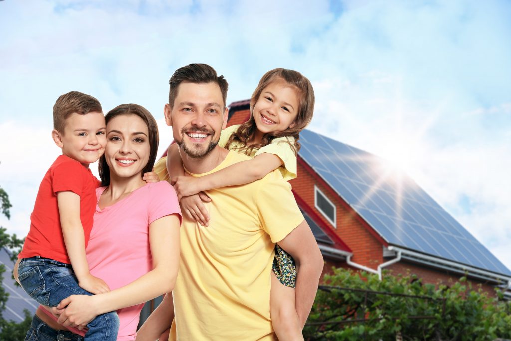 Family in front of a rural house with solar panels.